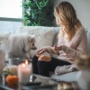 a person sitting on a couch with a dog and a candle